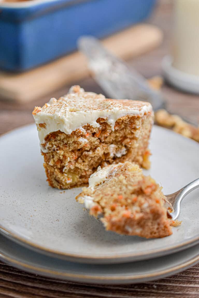 A piece of the sourdough discard carrot cake has a fork piece taken out of it.