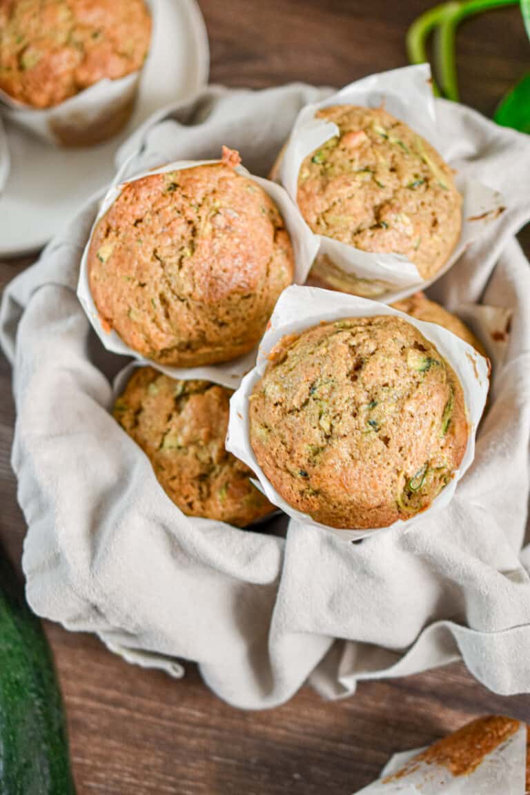 The sourdough discard zucchini muffins are piled high in a bowl.