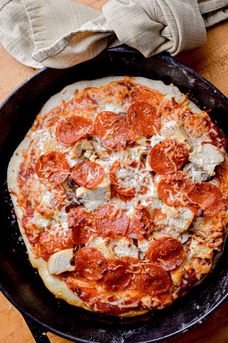 A towel is wrapped around the handle of the cast iron skillet that the sourdough pizza cooked in.