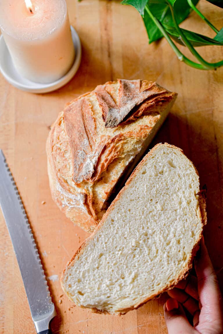 A serrated knife is next to a loaf of bread showing the tools needed for sourdough baking.