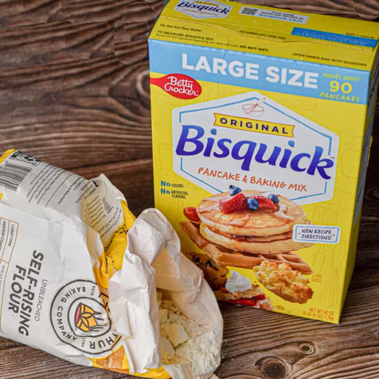 The self rising flour is being poured out in front of the box of bisquick.