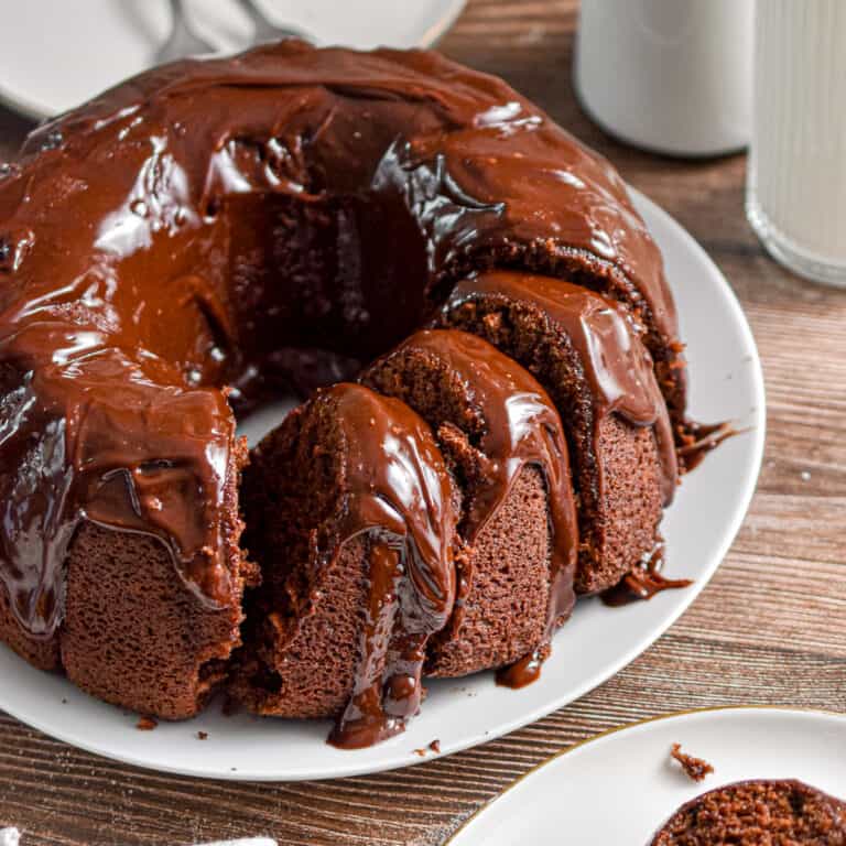 The sourdough chocolate cake is cut into pieces with a glass of milk behind it.