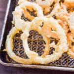 The sourdough discard onion rings are crispy and laid out on a baking sheet topped with a wire rack.
