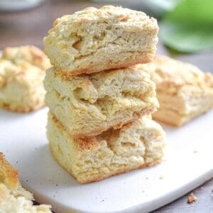 A stack of sourdough biscuits is on a white cutting board.