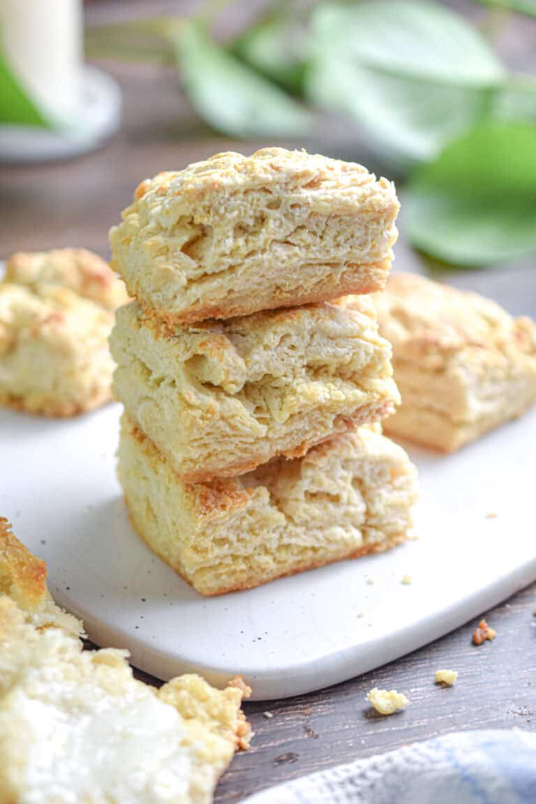A stack of sourdough biscuits is on a white cutting board.