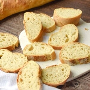 The slices of sourdough French bread are on a white cutting board.