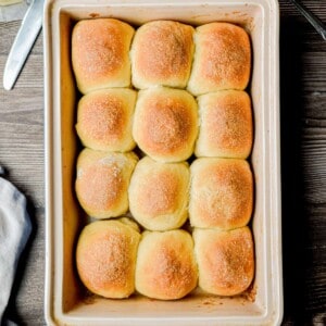 The pan of sourdough Hawaiian rolls is on a wooden background in a 9x13 inch pan.