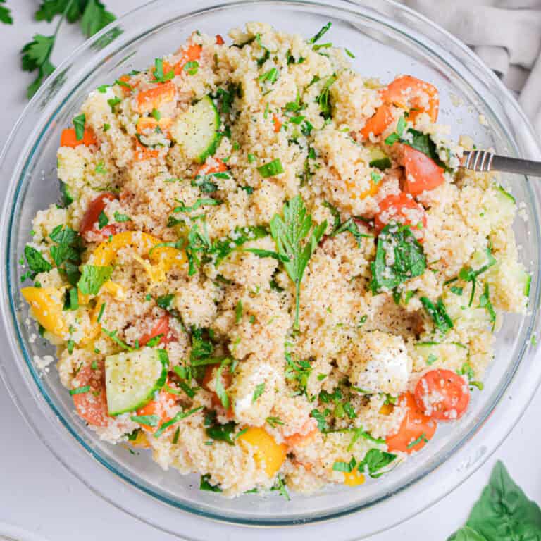 The summer couscous salad is in a large glass mixing bowl.
