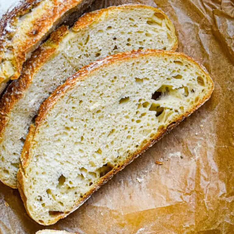Two slices of sourdough are on a brown parchment paper.
