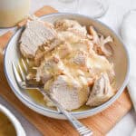 The Instant Pot turkey breast is in a bowl on a cutting board surrounded by a cloth napkin.