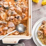 A spoon is in the pan with the sourdough bread pudding and a portion of the pudding is on a plate.