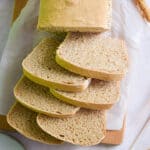 The whole wheat sourdough sandwich bread is sliced on a piece of crumpled parchment paper.