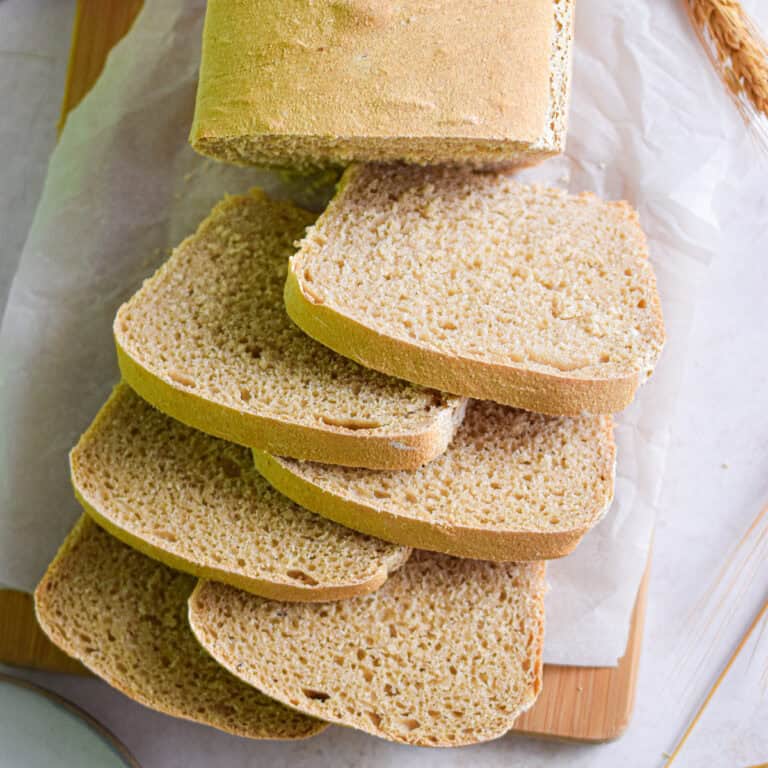 The whole wheat sourdough sandwich bread is sliced on a piece of crumpled parchment paper.