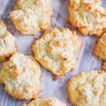 Drop biscuits with self rising flour are laid out on a parchment paper lined baking sheet.