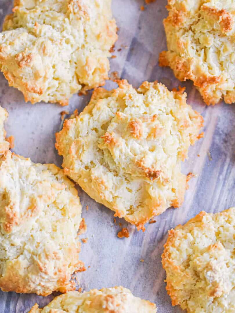 Drop biscuits with self rising flour are laid out on a parchment paper lined baking sheet.