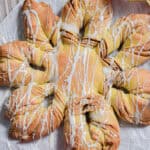 The sourdough star bread is on a piece of parchment paper drizzled with icing.