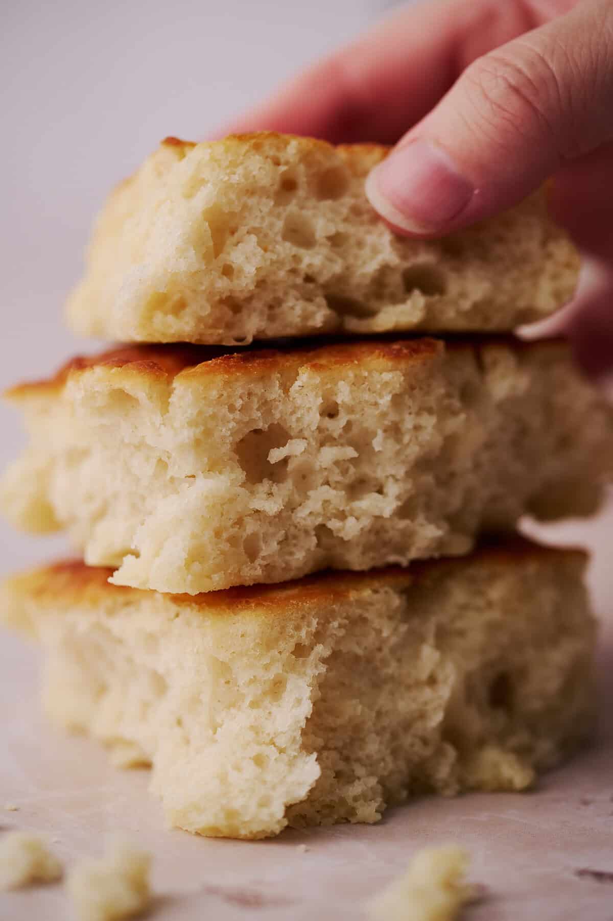 A hand is grabbing the top butter swim biscuit from a stack.