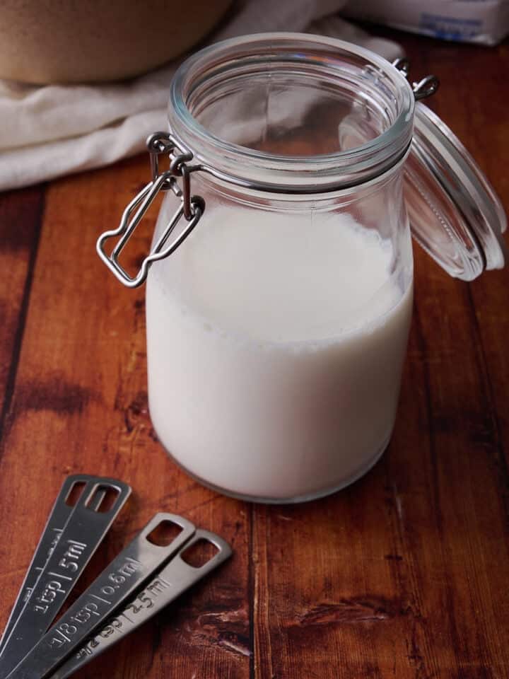 The buttermilk is in a small glass container with measuring spoons next to it.