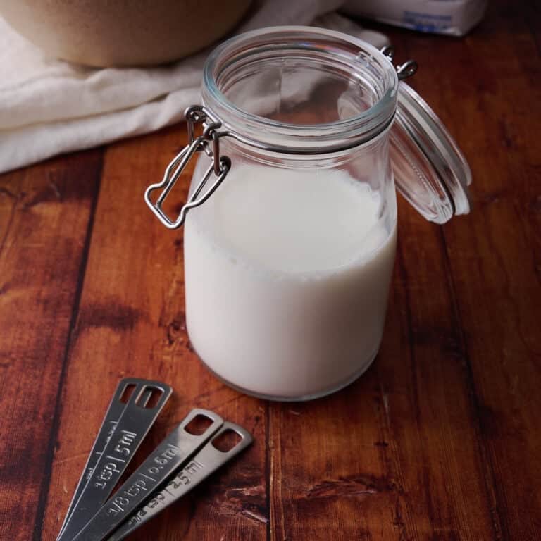 The buttermilk is in a small glass container with measuring spoons next to it.