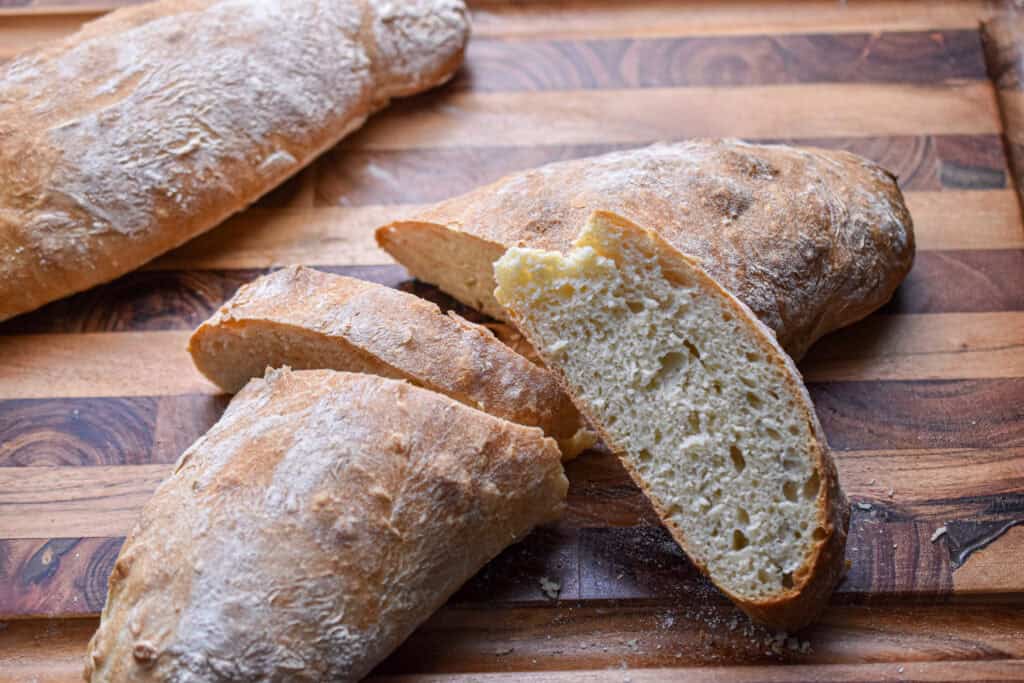 The ciabatta loaf is mostly together but there are two slices cut out of the middle.