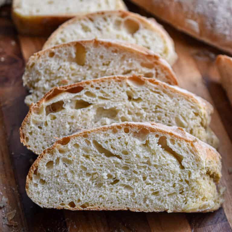 The sliced ciabatta bread are layered together to show the holes in the crumb.
