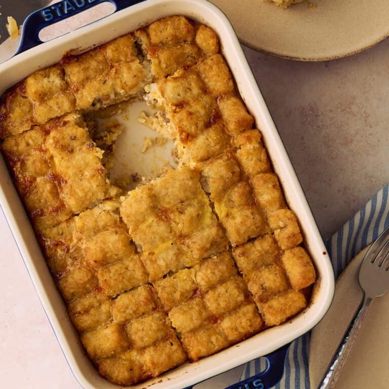 A square of the tater tot casserole is taken out of the baking dish.