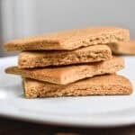 The sourdough graham crackers are stacked on top of each other on a white plate.