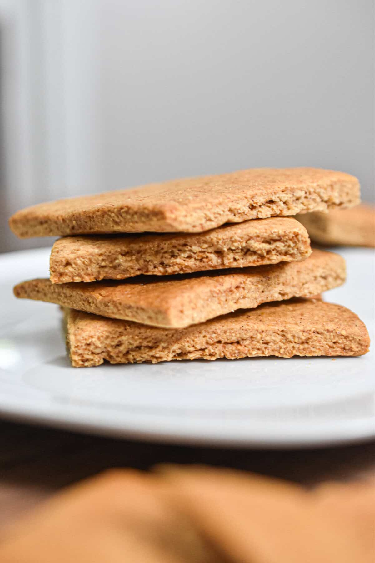 The sourdough graham crackers are on a white plate stacked on top of each other.