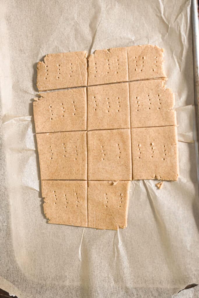 The graham crackers are cut and on a piece of parchment paper.