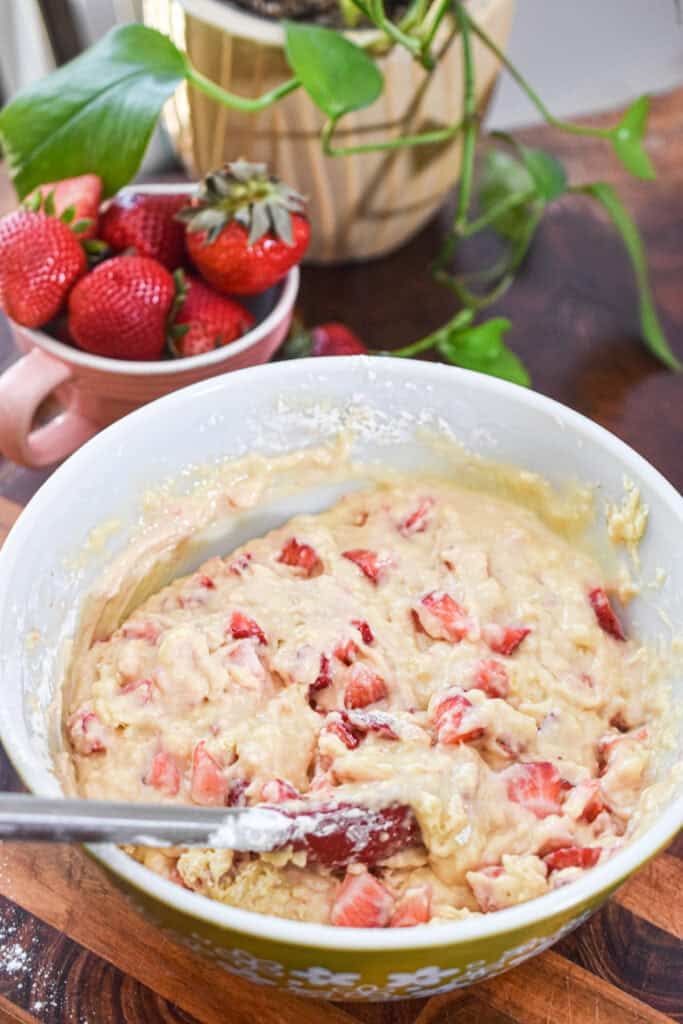 Fresh strawberry muffin batter in a bowl with chopped strawberries.