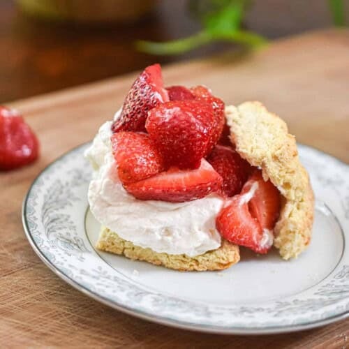 Strawberries are piled high on the whipped cream and biscuits.