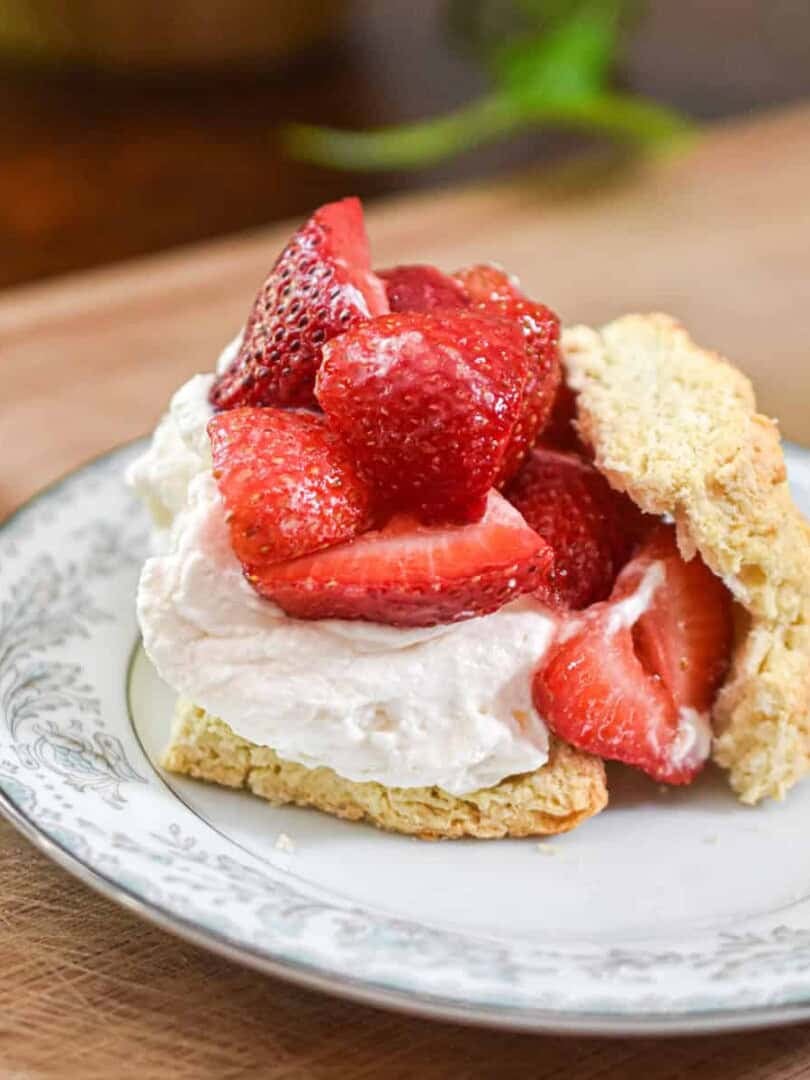 Strawberries are piled high on the whipped cream and biscuits.