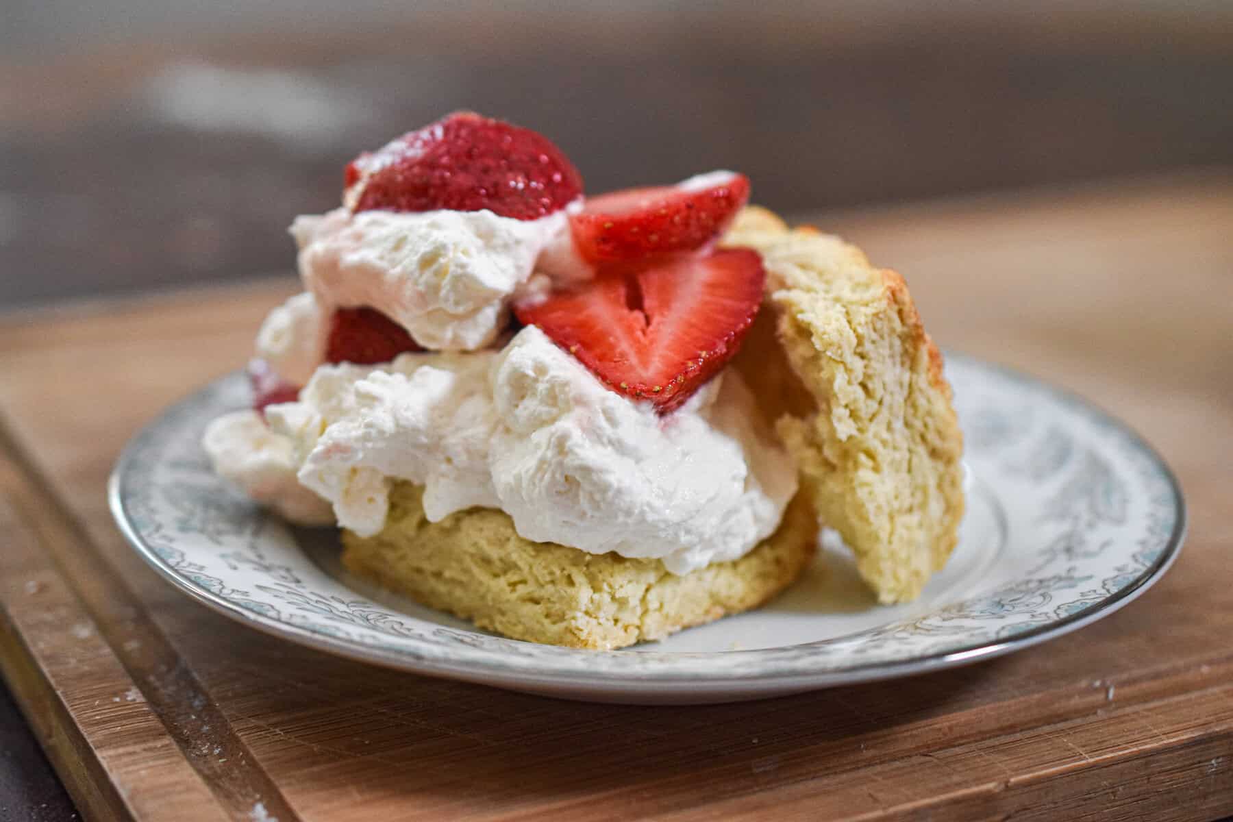 The biscuit is cut in half and the whipped cream and strawberries are on top of them.