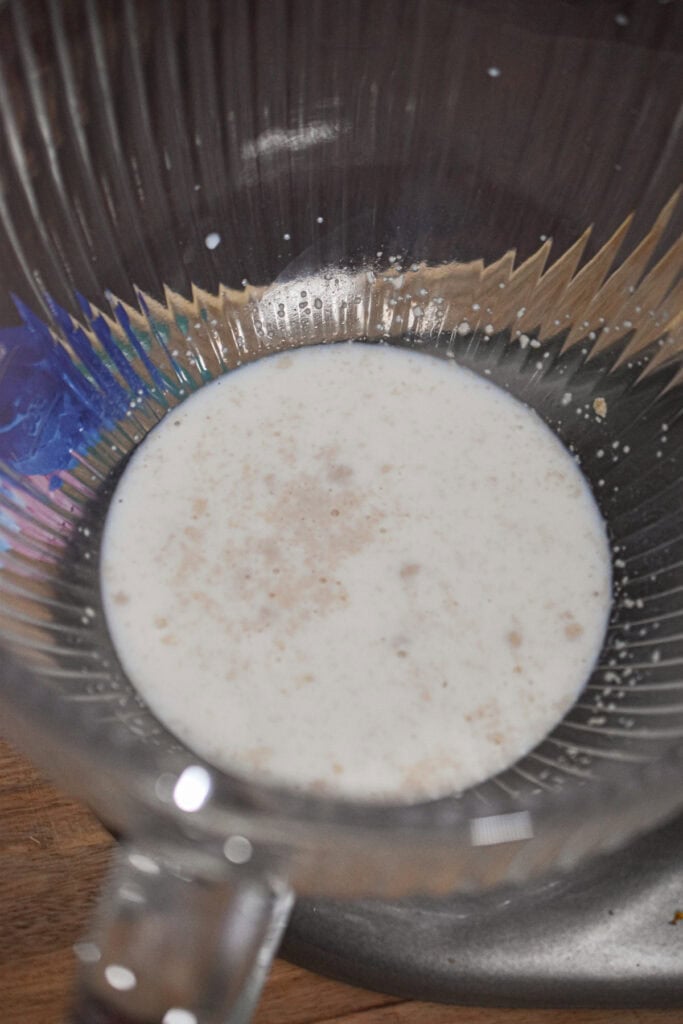 The milk and yeast are in the bowl of a stand mixer.