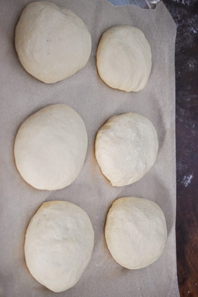 The buns are on a parchment lined baking sheet.