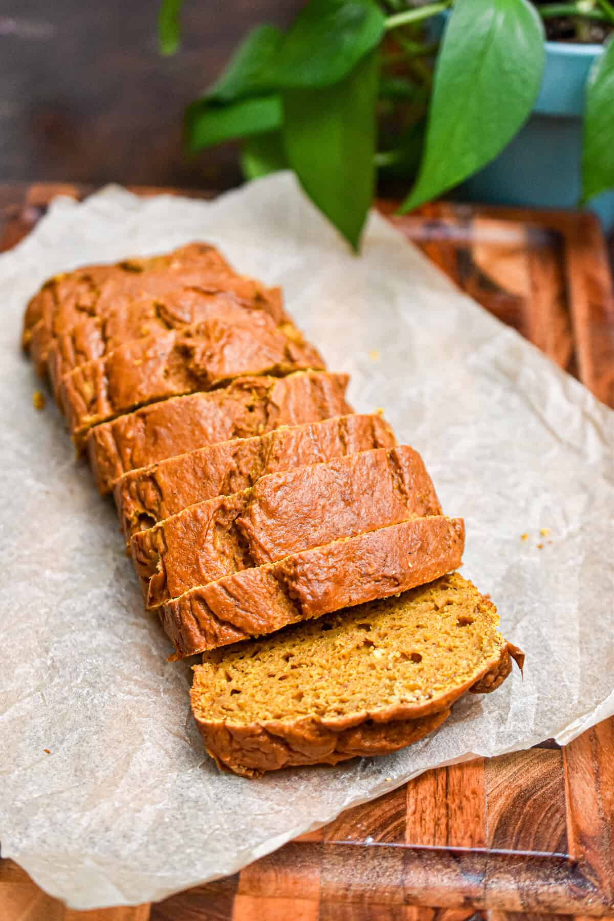 The 5 ingredient pumpkin bread is sliced and on a piece of parchment paper.