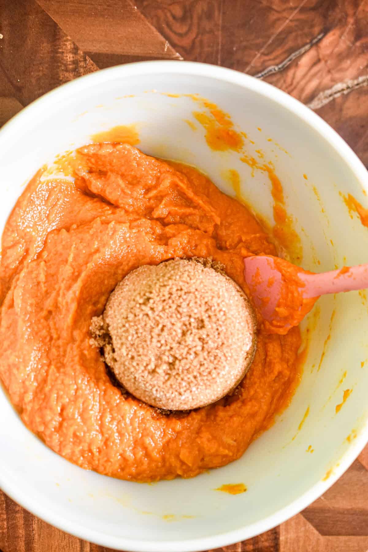 The brown sugar and pumpkin are added to a large bowl.