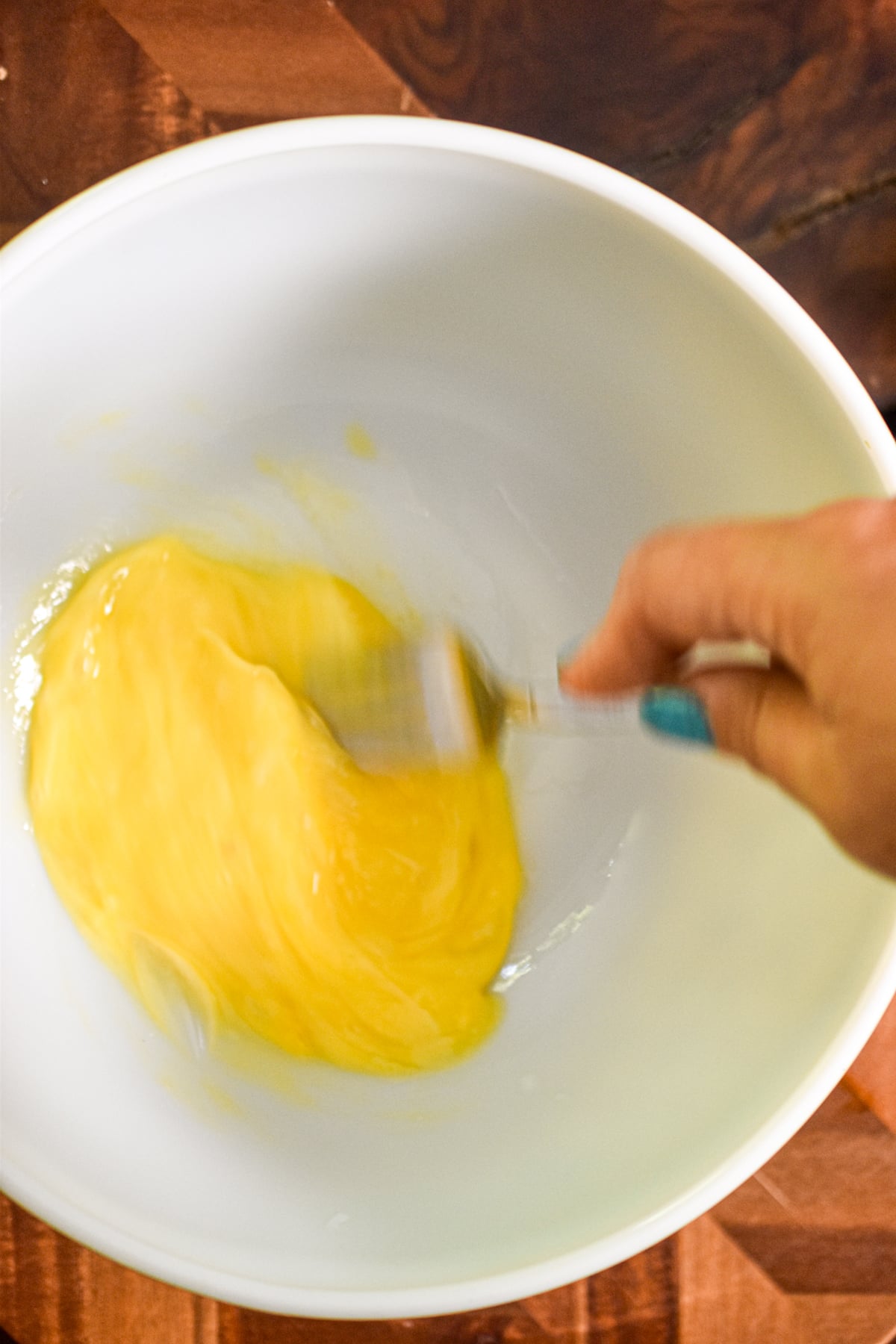 A fork is whisking the eggs together.