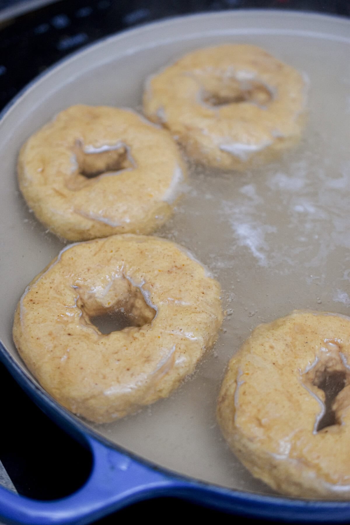 The bagels are in a pot boiling.