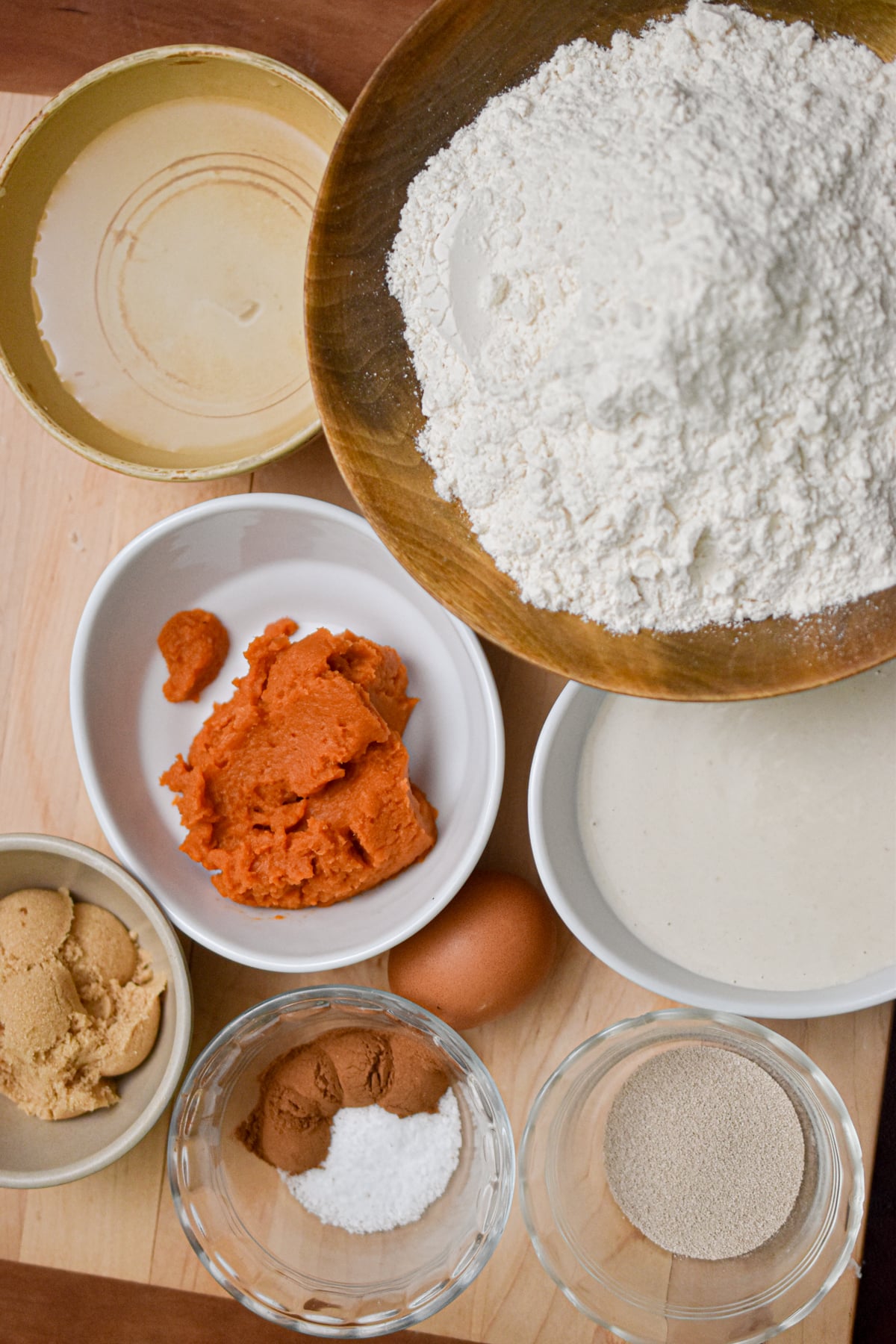 The ingredients for the sourdough discard pumpkin bagel are on a wooden cutting board.