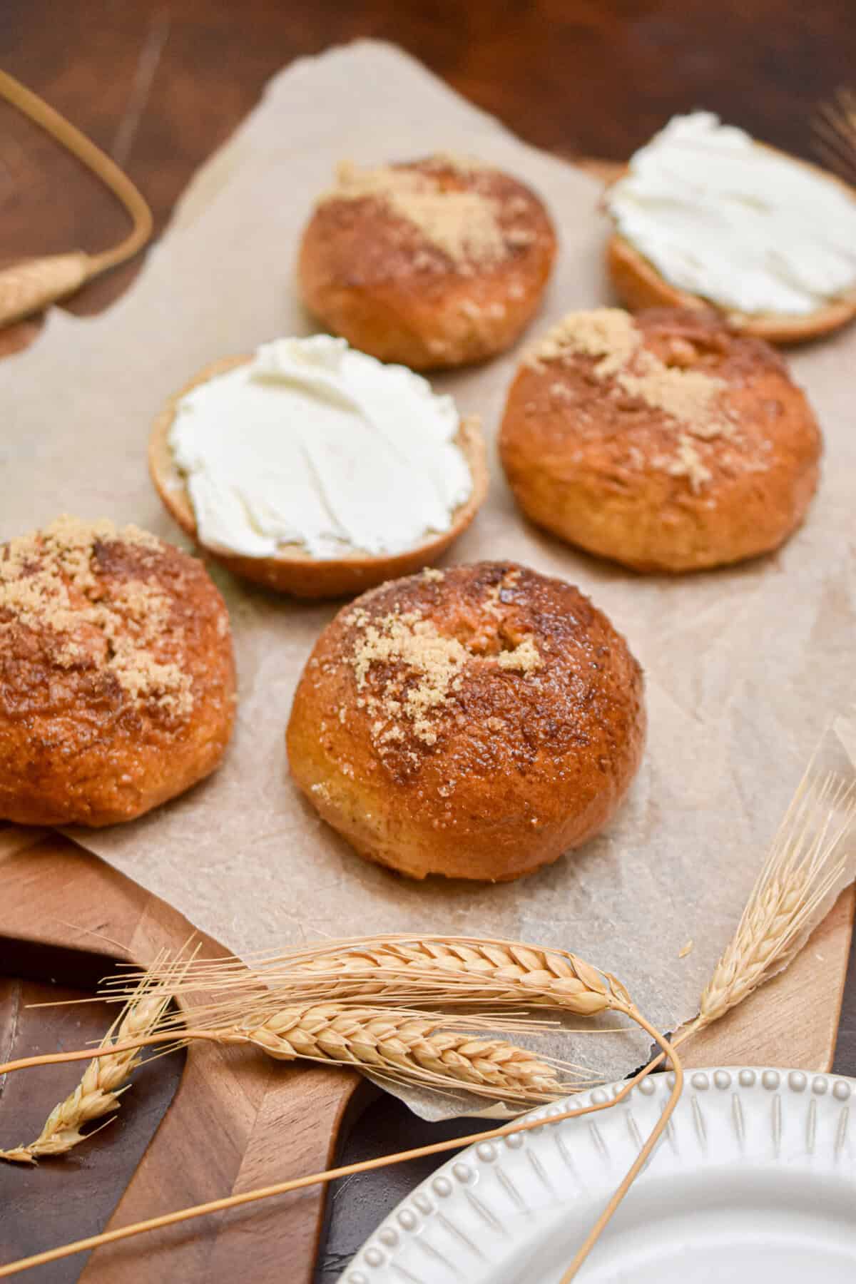 The sourdough discard pumpkin bagels are on a piece of parchment paper and some are cut in half with cream cheese all over the bagels.