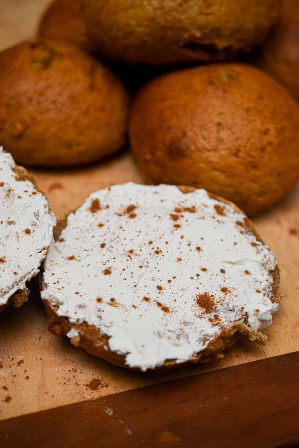 The half of a sourdough pumpkin bagel is shmeared with cream cheese and sprinkled with pumpkin spice.