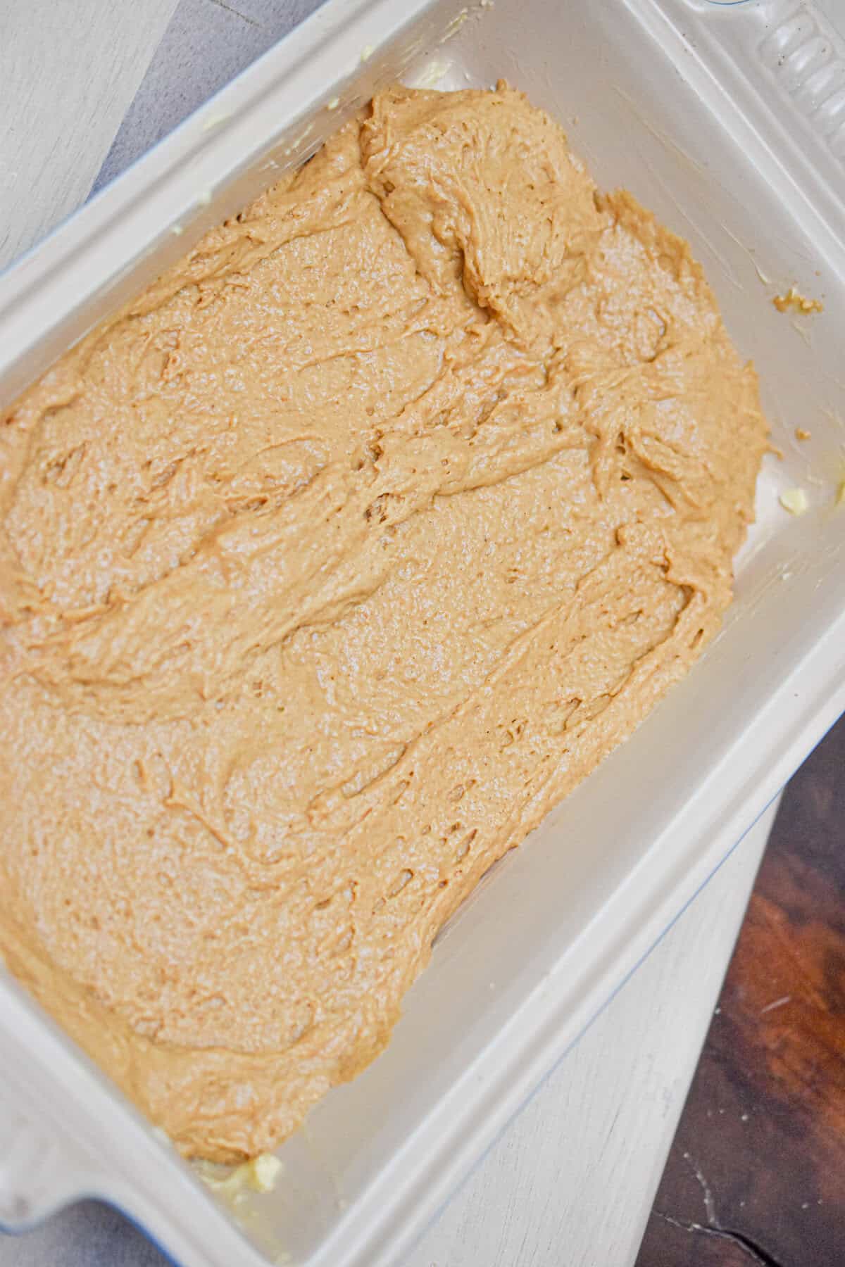 The cake batter is added to a baking dish.
