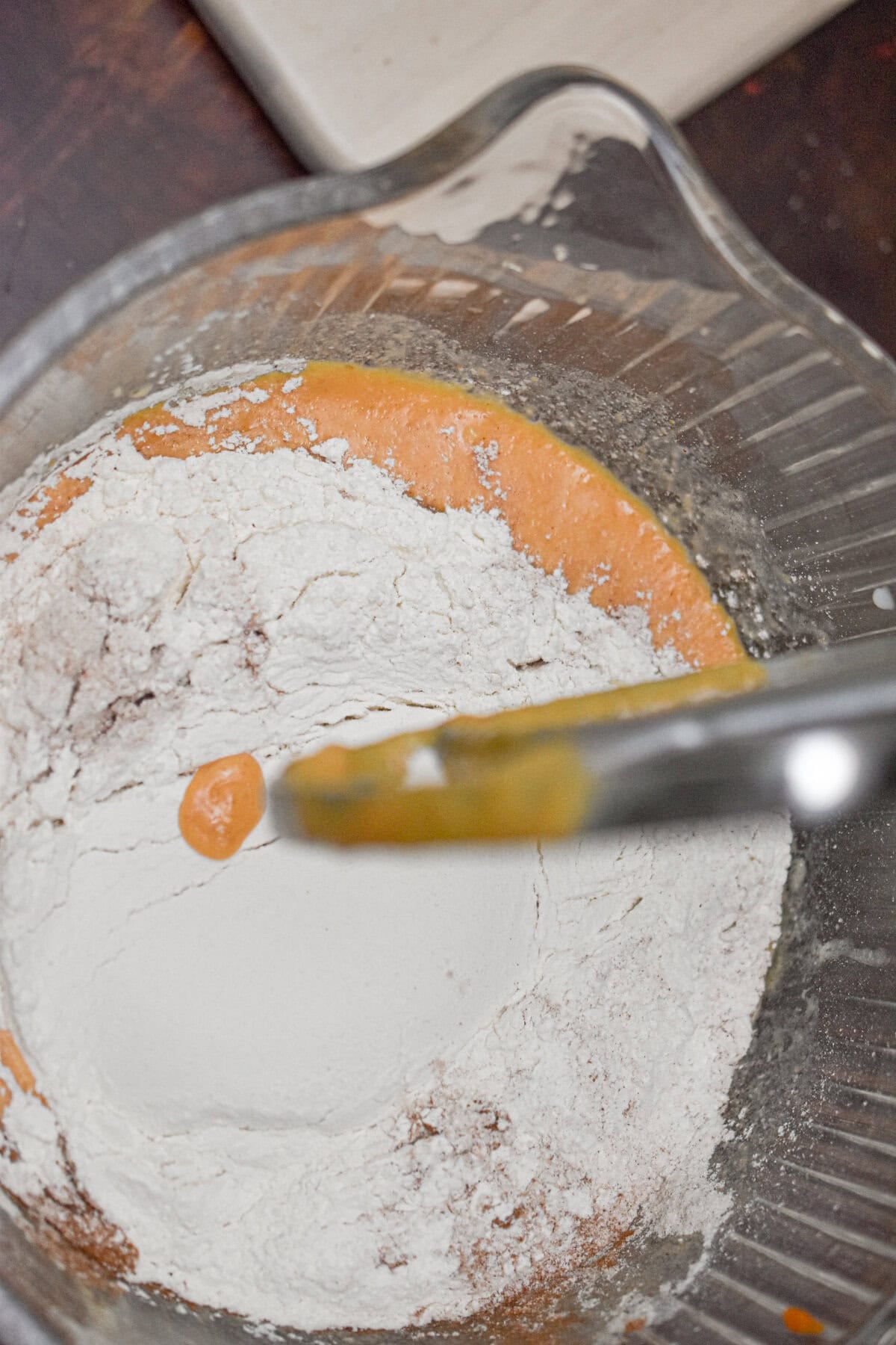 The dry ingredients are added to the wet ingredients in a stand mixer.