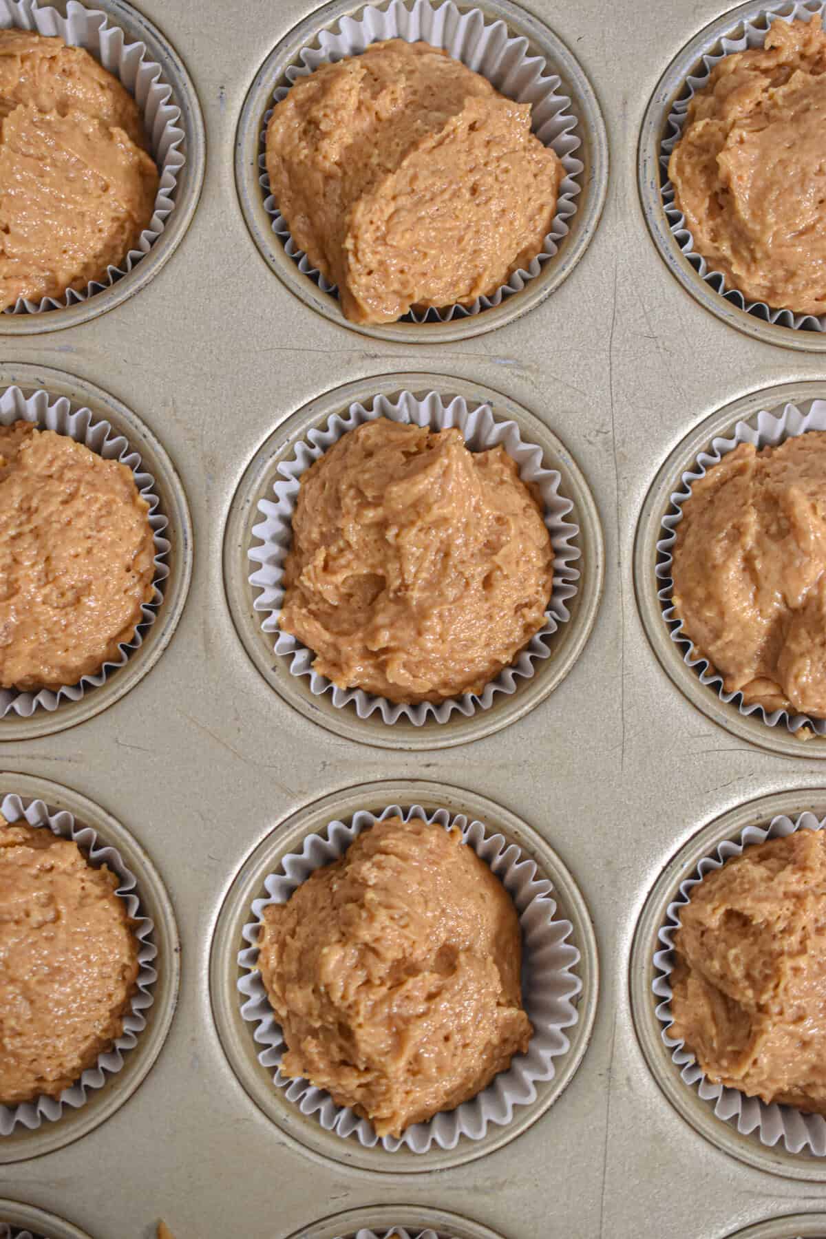 The batter for the pumpkin muffins with self rising flour are added to the muffin tin.