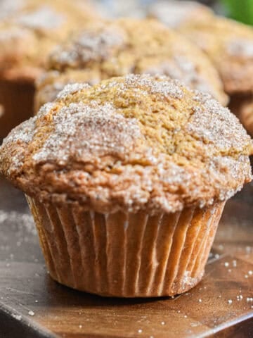 The pumpkin muffin with self rising flour is on a cutting board with more muffins in the background.