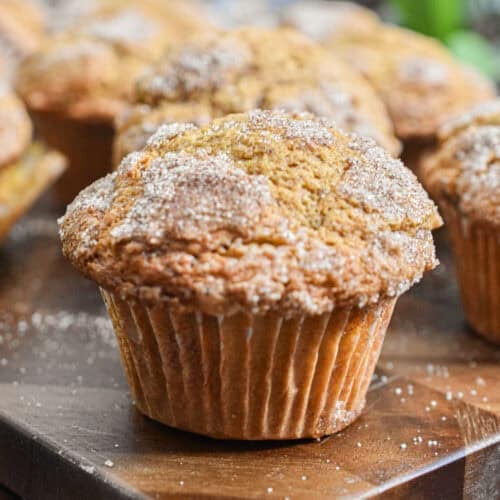 The pumpkin muffin with self rising flour is on a cutting board with more muffins in the background.