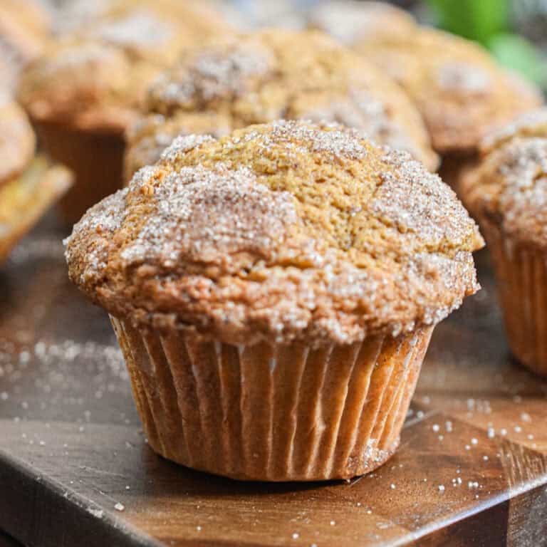 The pumpkin muffin with self rising flour is on a cutting board with more muffins in the background.