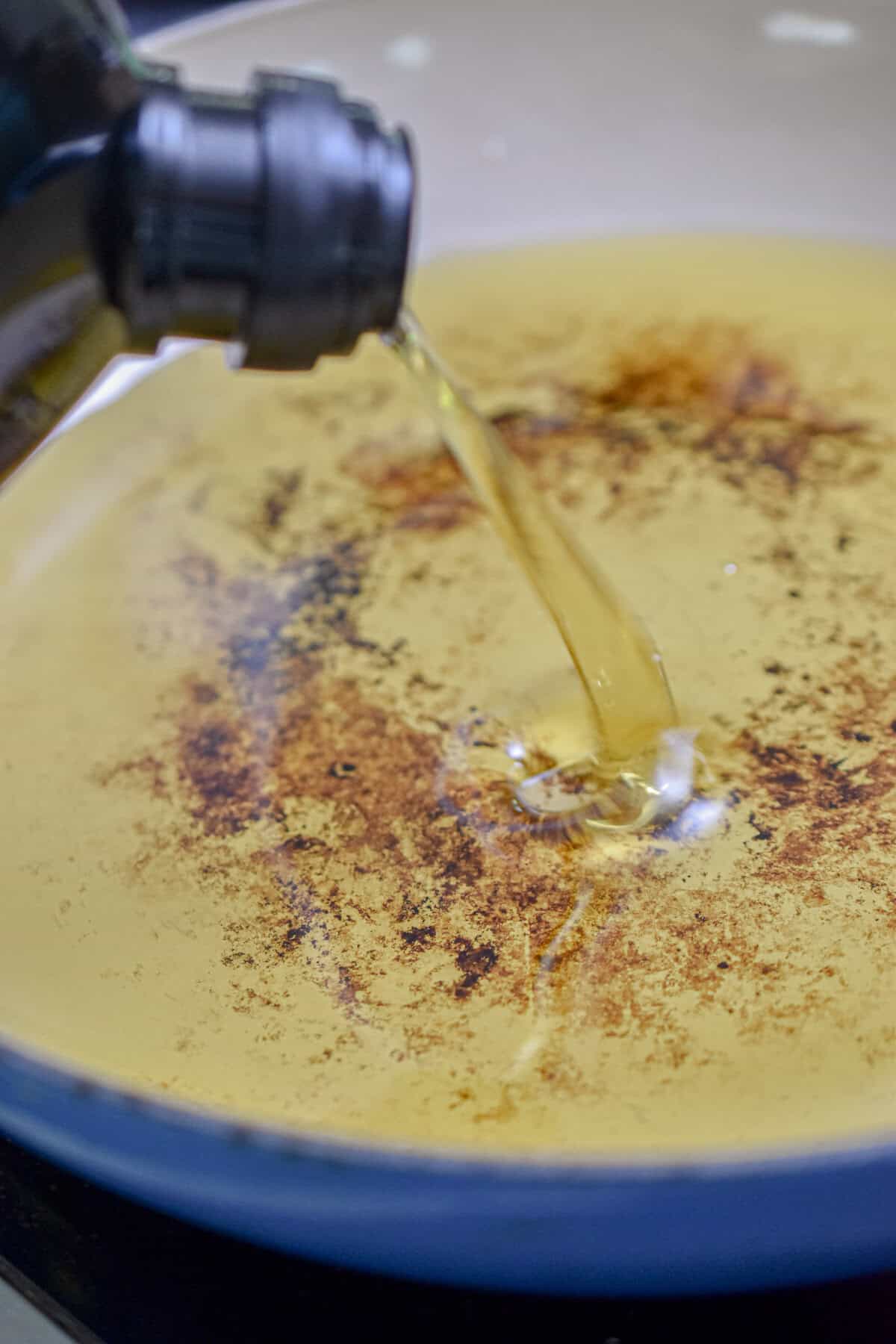 Oil is being poured into a Dutch oven.