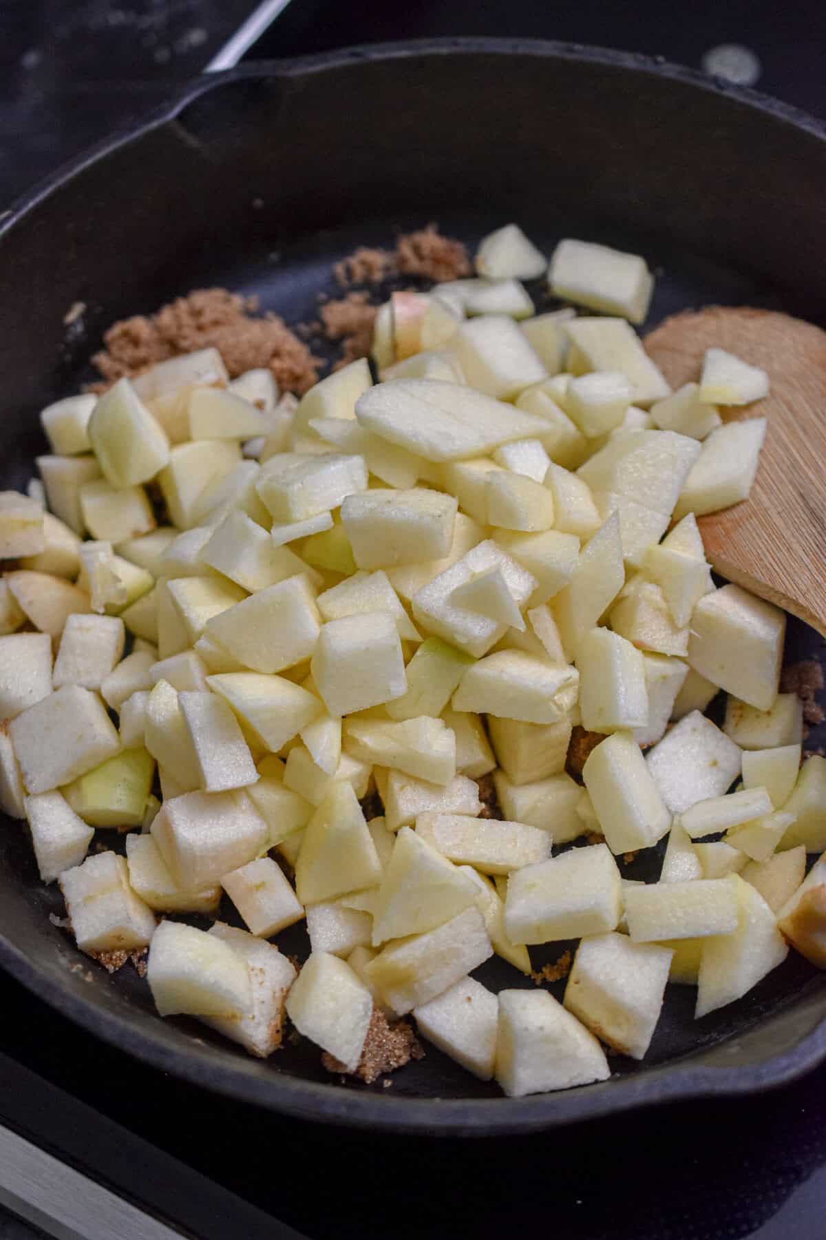 The apples, brown sugar, and butter are in a cast iron skillet.